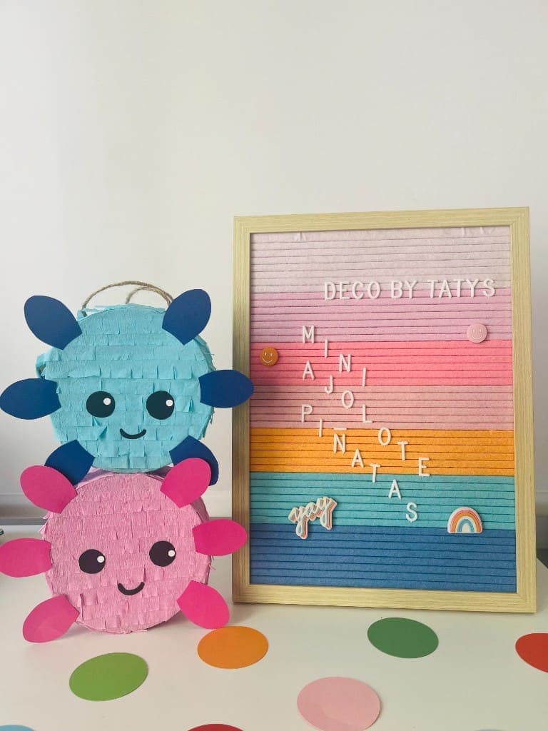 Blue and pink mini axolotl piñatas beside a Deco By Tatys letter board